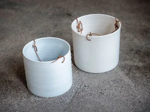 Two white ceramic plant holders with a leather string to hang it up.
To the left is the copycat made by Netto and to the right is the original design by Anne Black 